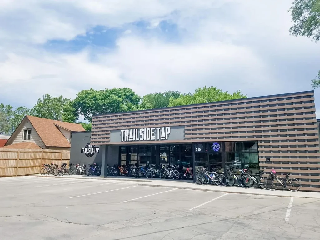 Modern TRAILSIDE TAP building with an OPEN sign and many bikes.
