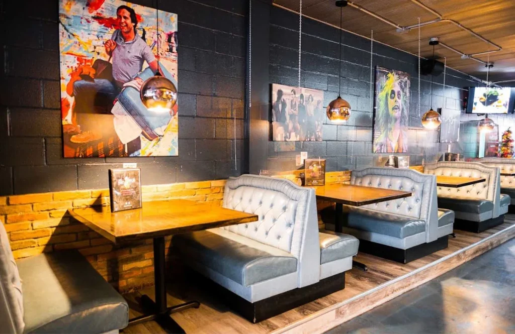 Restaurant with tufted booths, diverse art, exposed brick, and industrial ceiling.