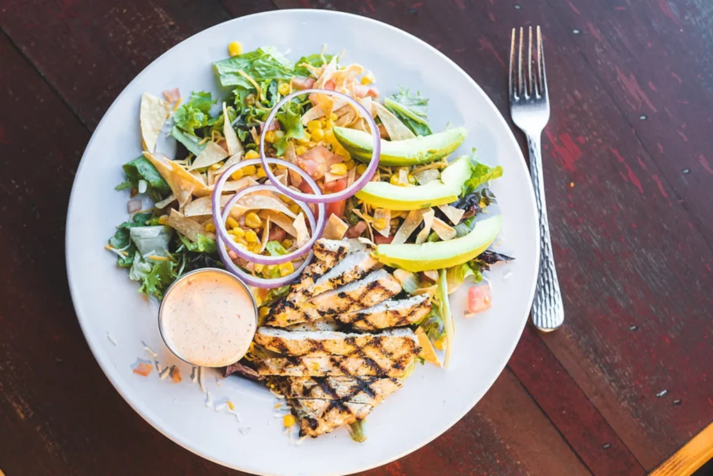 Colorful grilled chicken salad with avocado, corn, and creamy dressing.
