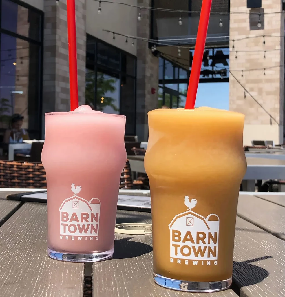 Frosty pink and amber drinks in Barn Town Brewing glasses outdoors.