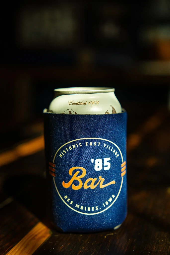 Beverage can in blue koozie with '85 Bar Des Moines text.
