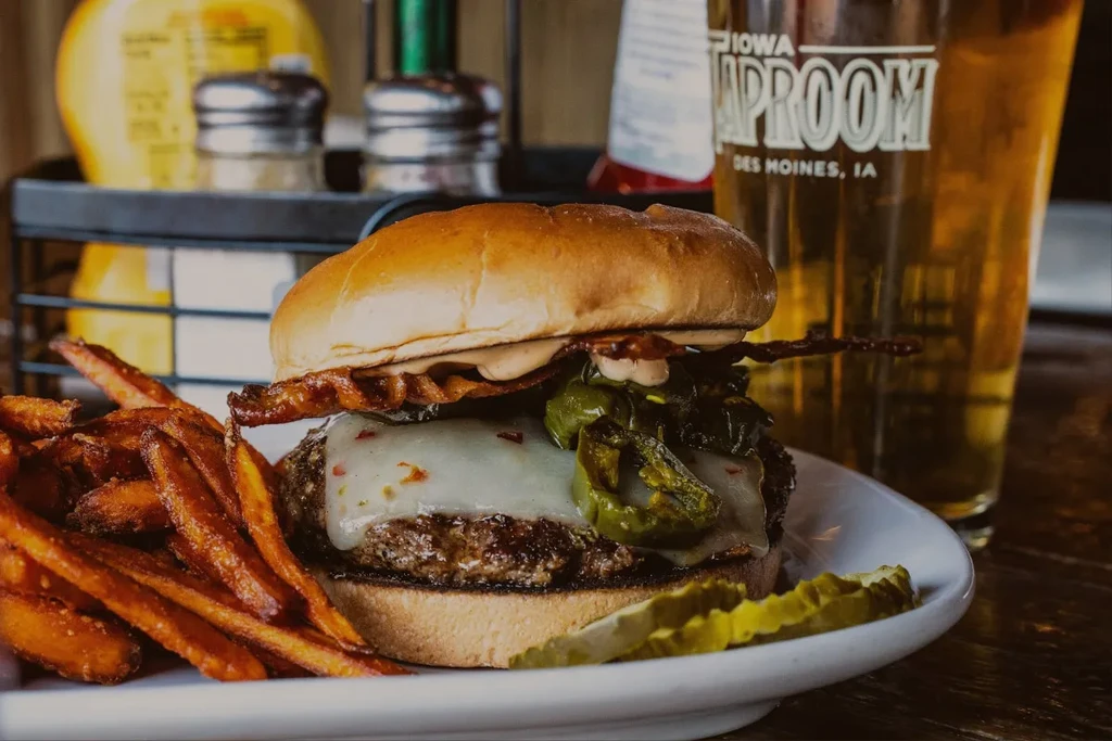 Gourmet burger with bacon, sweet potato fries, and Iowa Taproom beer.