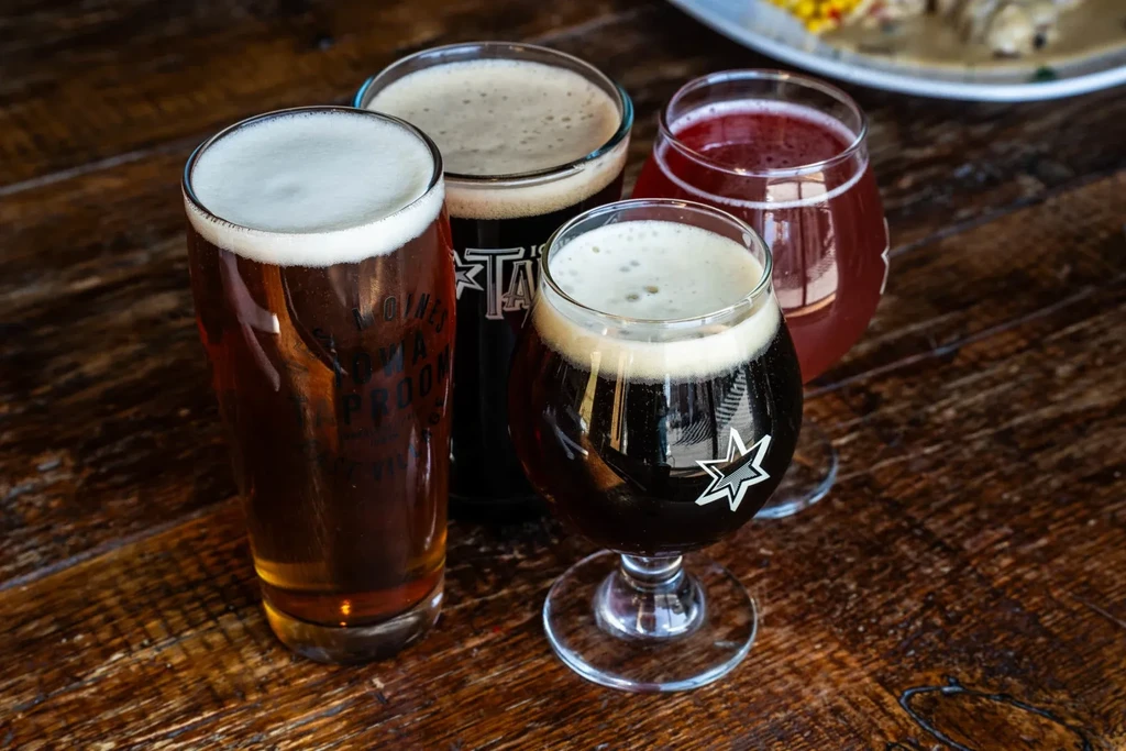 Four diverse craft beers and beverages on a wooden table.