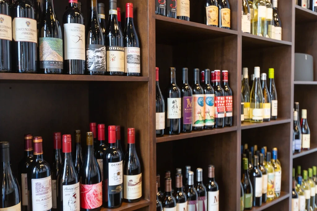 Dark wooden shelves neatly display many red and white wine bottles.