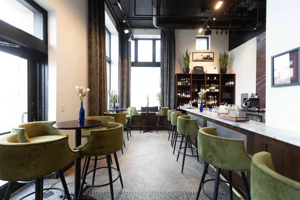 Chic modern bar with olive green velvet seating and dark industrial ceiling.
