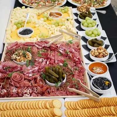 Buffet display of meats, cheeses, fruits, nuts, pickles, and crackers.
