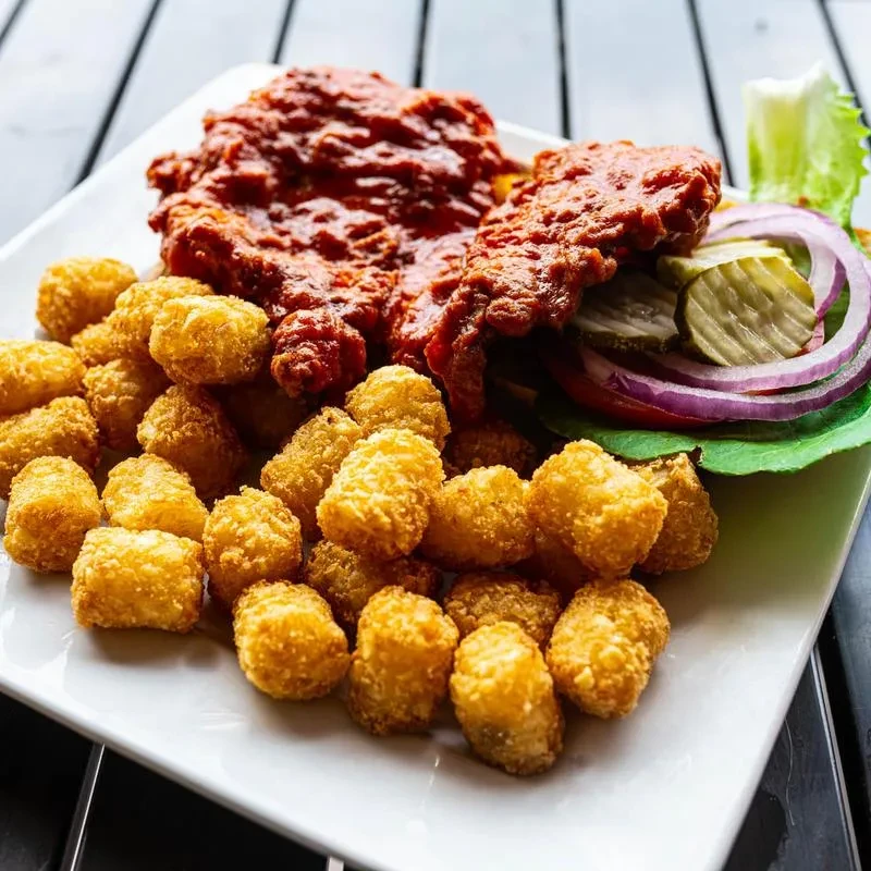 Crispy tater tots, spicy fried chicken, lettuce, tomato, onion, and pickles.