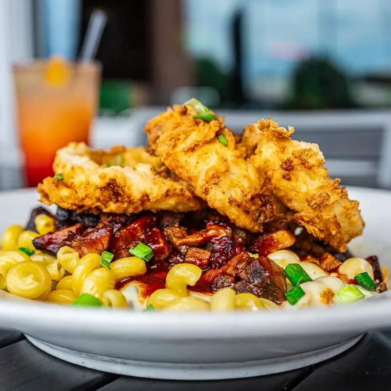 Macaroni and cheese topped with saucy meat, fried chicken, and green onions.