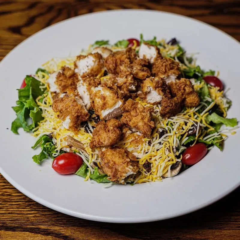 Fried chicken salad with mixed greens, cheese, olives, and tomatoes.