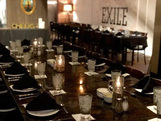 Candlelit long wooden dining table set in "EXILE" restaurant.