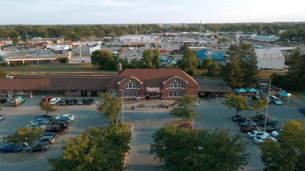 Aerial view of "CORN BREAD" restaurant with outdoor dining, tracks, and parking.