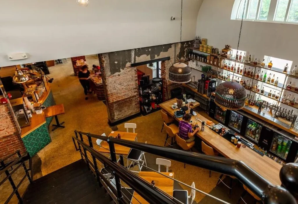 Multi-level industrial-chic restaurant interior with bar, counter, and stairs.