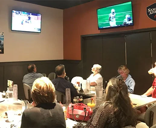 Patrons watch football on two TVs in a casual sports bar.