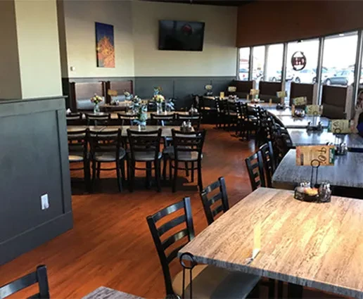 Empty, well-lit restaurant dining area with set tables, chairs, and booths.