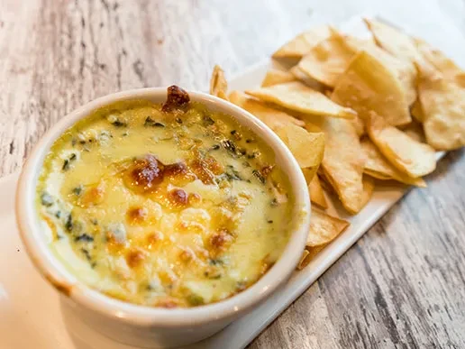 Cheesy baked dip in ramekin with crispy tortilla chips.