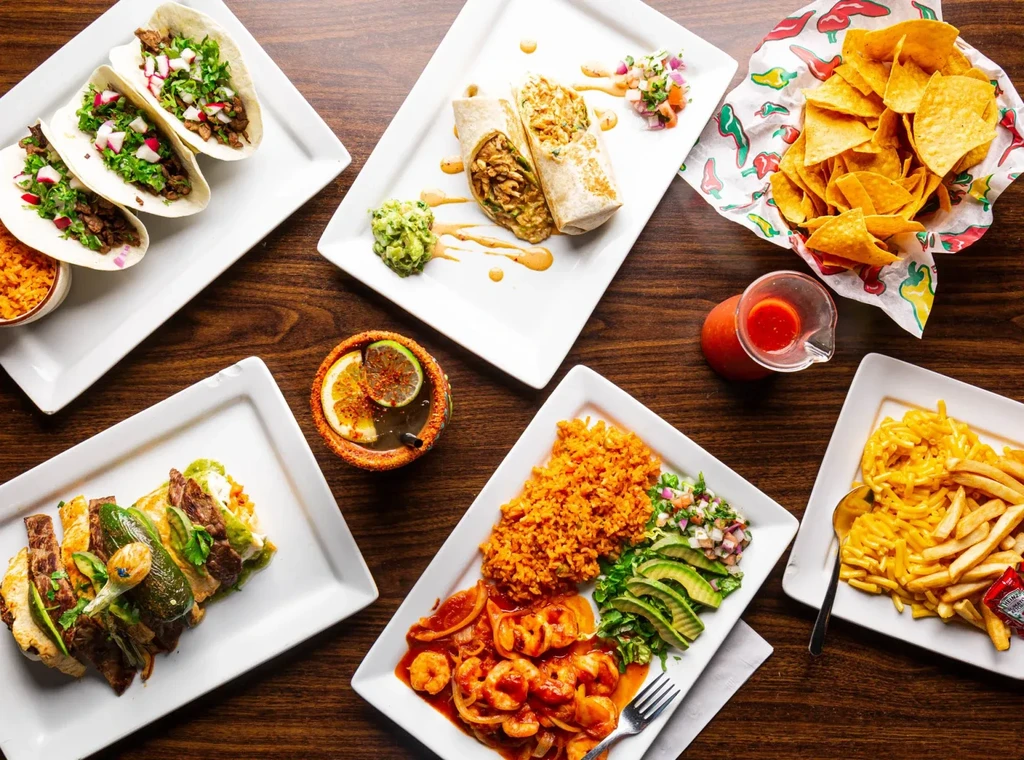 Top-down view of a wooden table laden with Mexican dishes and drinks.