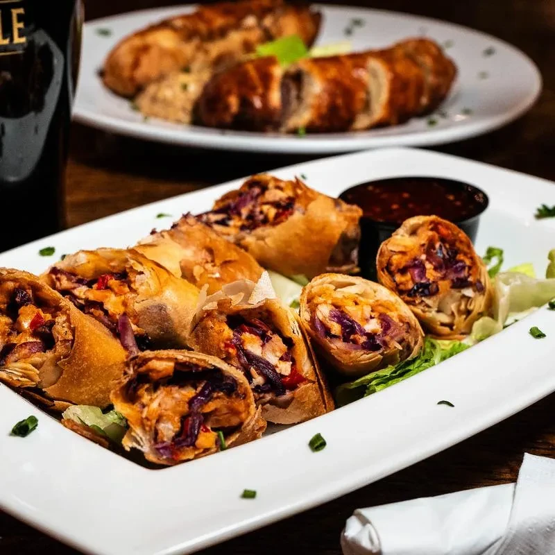 Deep-fried rolls cut in half, revealing colorful vegetable and meat filling.