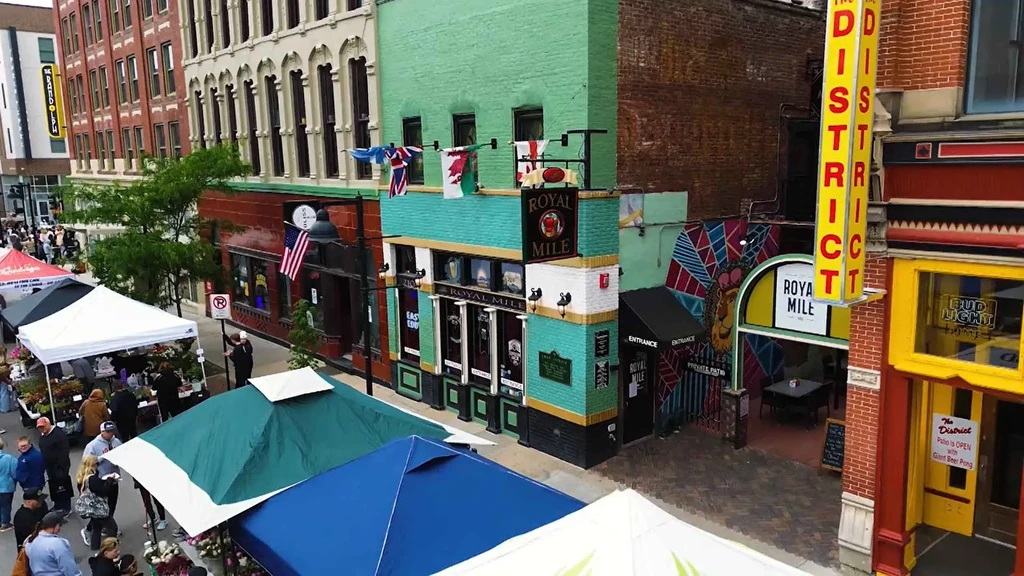 Teal Royal Mile building overlooks a bustling outdoor market with many tents.