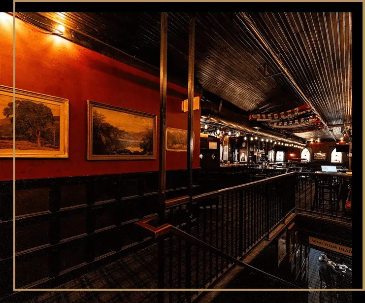 Traditional pub interior with red walls, framed art, and dark wood.