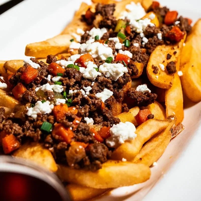 Crispy loaded potato wedges with ground meat, cheese, vegetables, herbs.