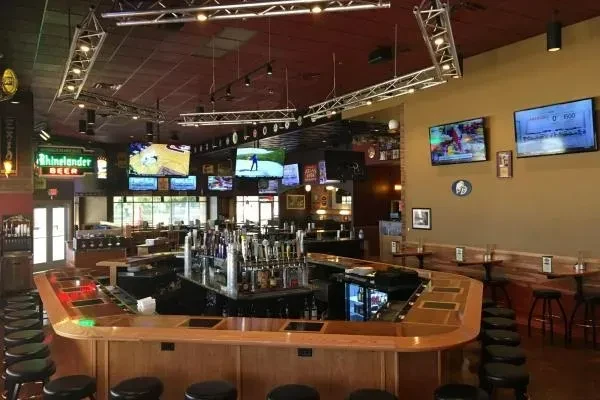 Sports bar interior with a large bar, beer taps, and TVs showing sports.