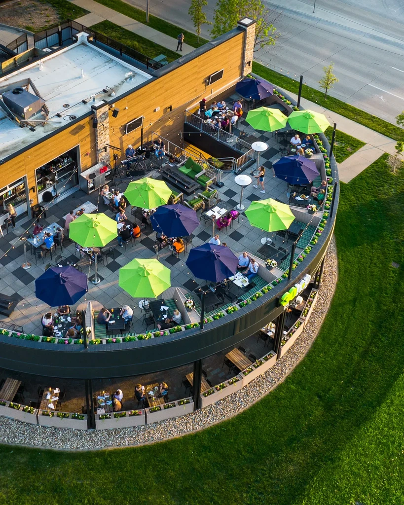 Aerial view of multi-level restaurant patios with patrons and colorful umbrellas.
