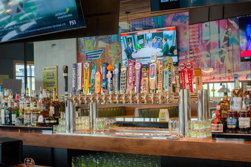 Well-stocked bar with many beer taps, liquor bottles, and TVs.