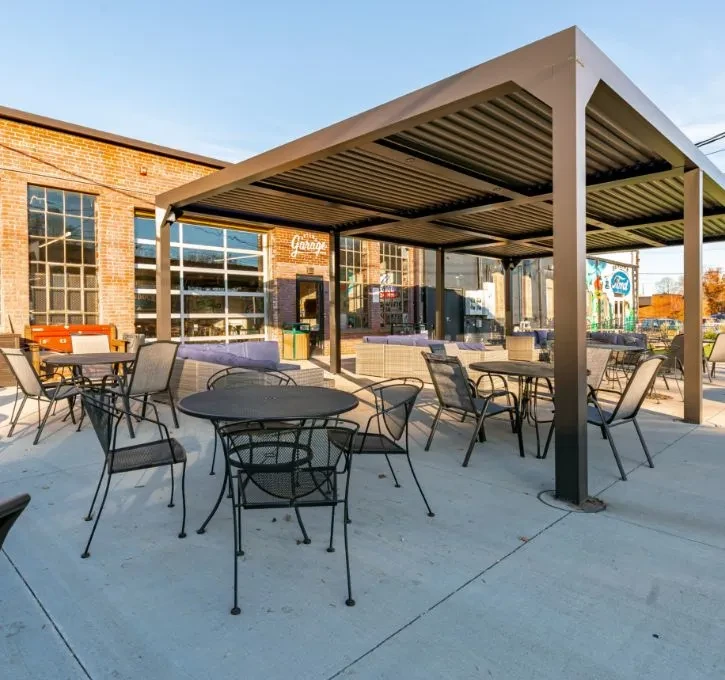 The Garage patio with modern pergola, metal tables, and purple seating.