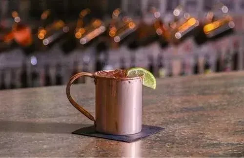 Copper mug drink with ice and lime on a bar counter.