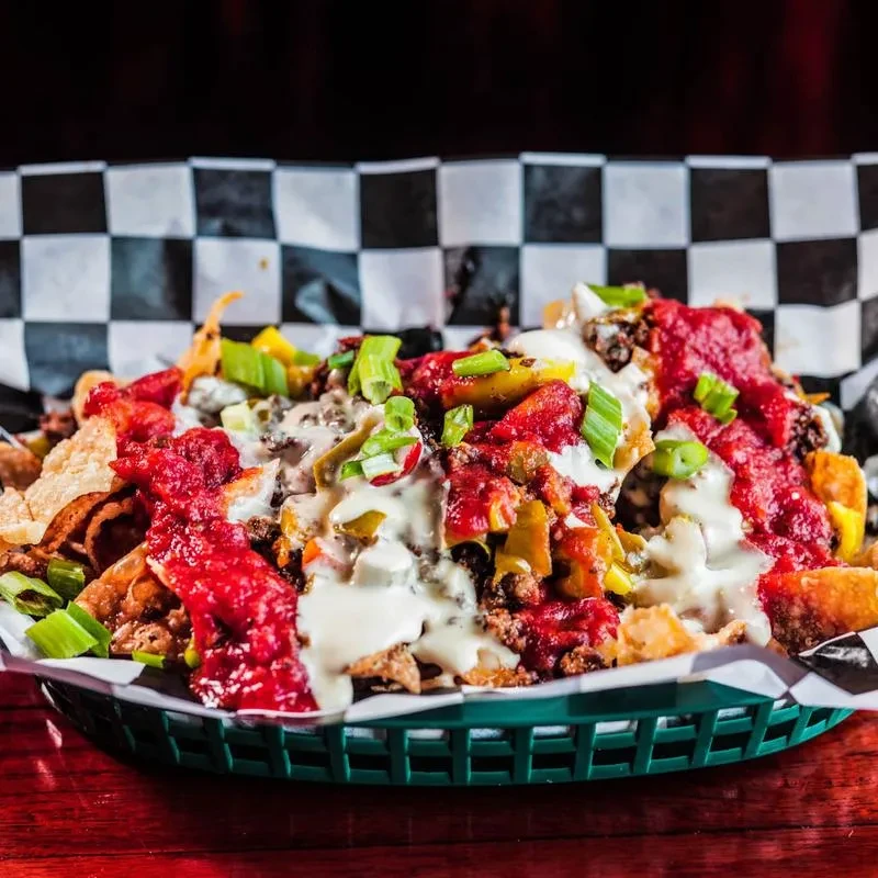 Loaded nachos with meat, cheese, red sauce, green onions, jalapeños.