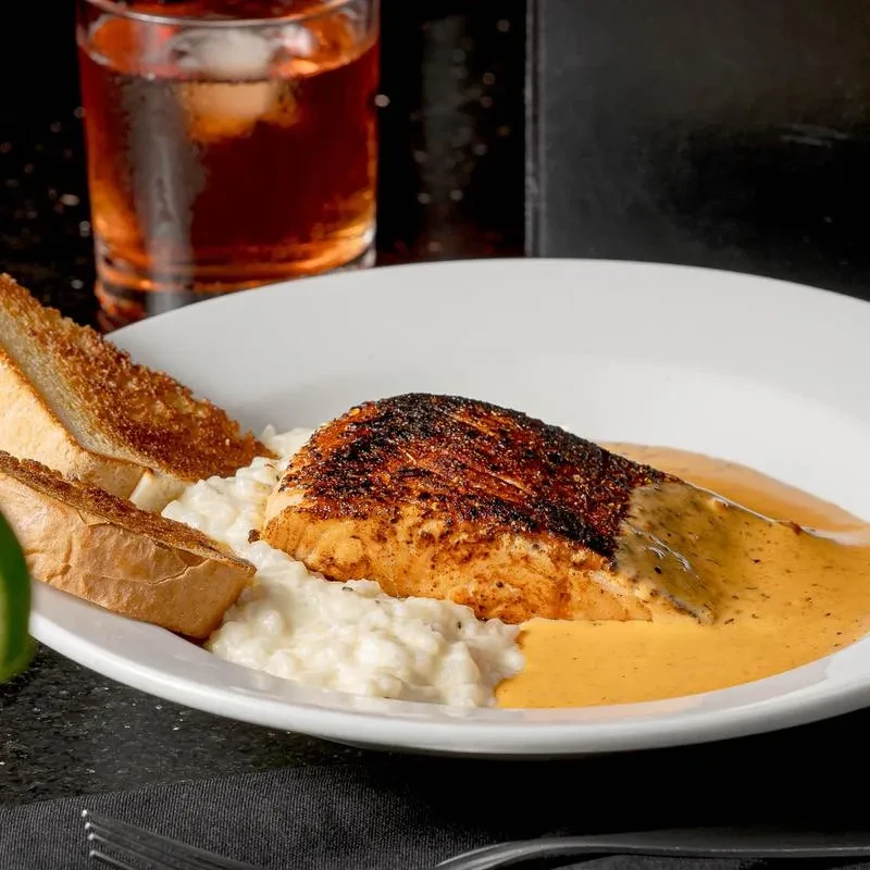 Seared fish, dark crust, orange sauce, creamy base, and toast.