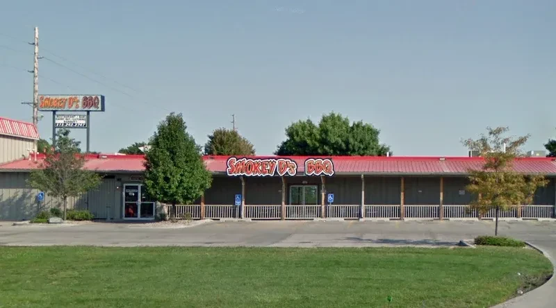 Smokey D's BBQ restaurant exterior with red roof, grey siding, parking.