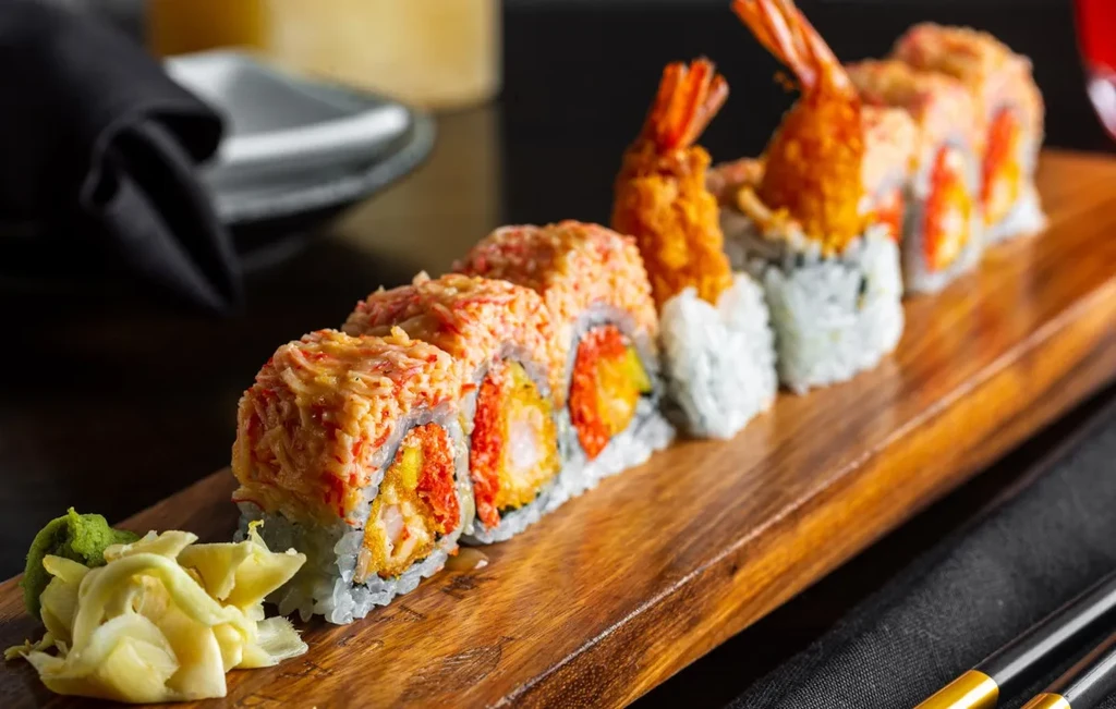Specialty sushi rolls with tempura and crab on a rustic wooden platter.