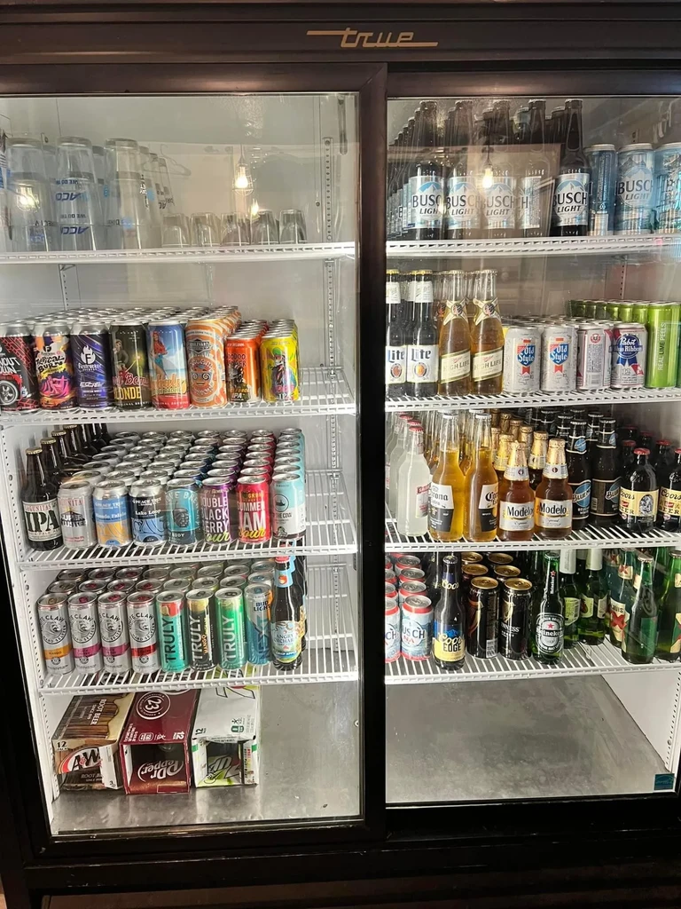 True commercial glass-front refrigerator stocked with various beverages and glasses.