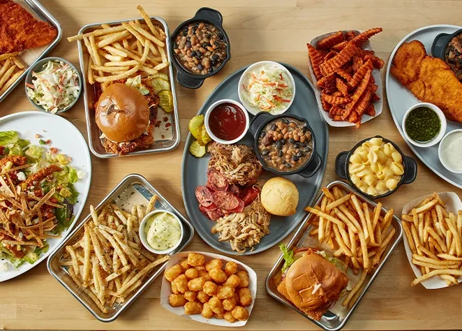 Overhead view of a lavish spread of comfort food on a wooden table.