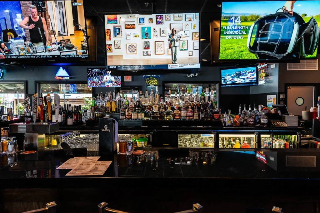 A well-stocked bar area with liquor bottles and multiple TVs.
