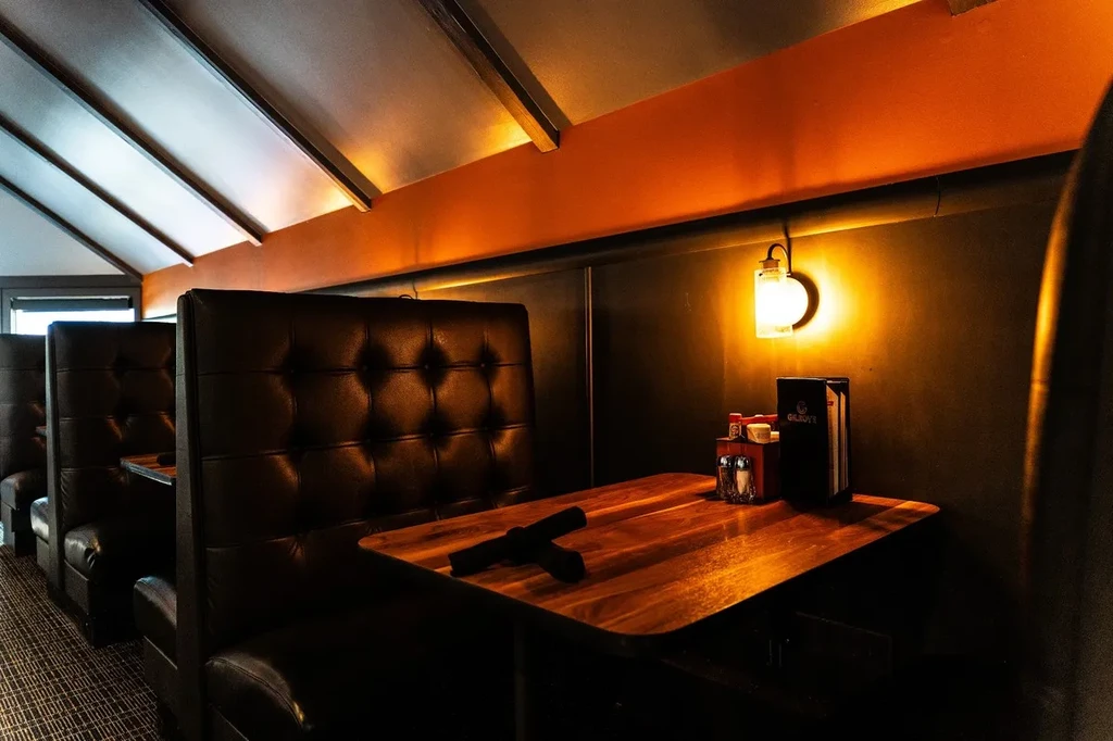 Warmly lit restaurant interior with tufted booths and a set table.