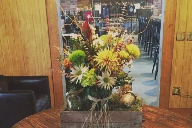 Colorful flowers in mason jars, a centerpiece on a rustic restaurant table.