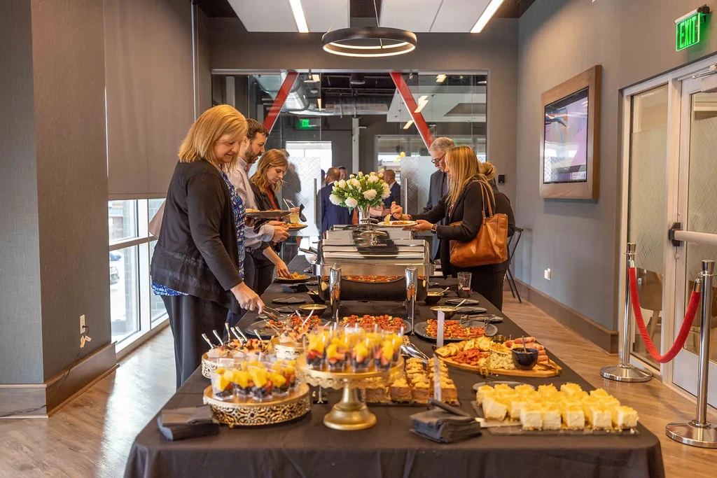 Guests serving themselves from a diverse buffet in a modern event space.