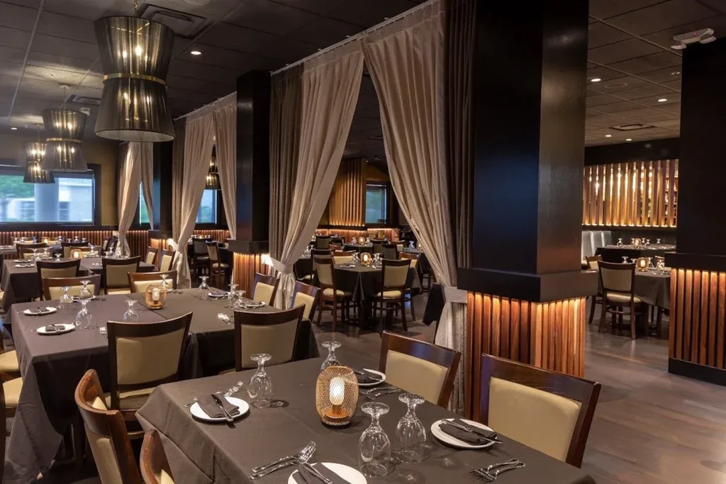 Dimly lit empty restaurant dining area with set tables and lanterns.