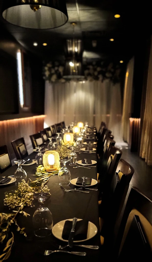 Dimly lit elegant dining table with glowing lanterns, place settings, floral decor.