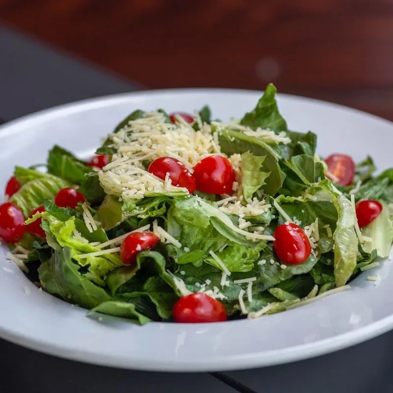Close-up salad: lettuce, red cherry tomatoes, and shredded white cheese.