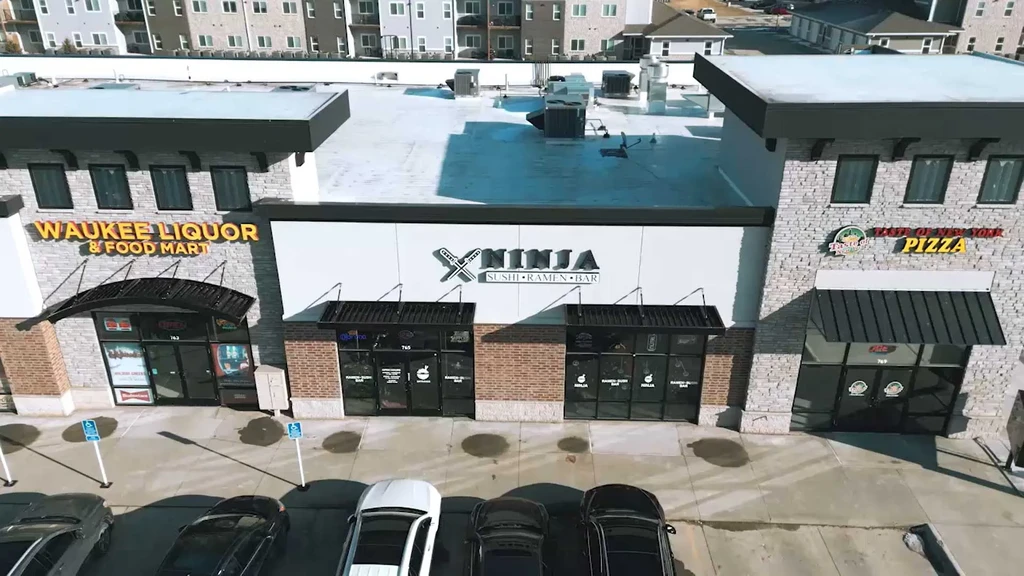 Modern strip mall with a liquor store, sushi, and pizza restaurant.