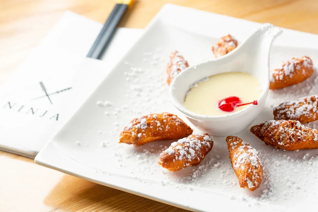 Powdered sugar pastries with cherry sauce, "NINJA" menu visible.