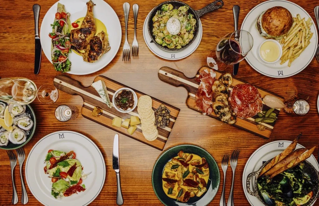 Overhead view of a wooden table laden with diverse gourmet food.