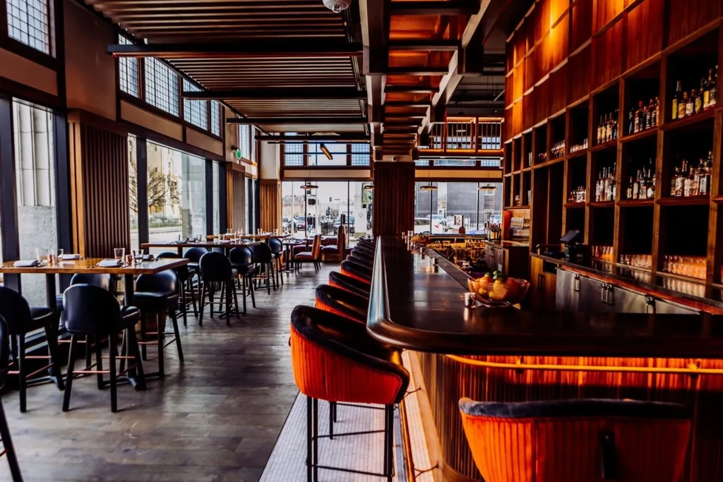 Modern upscale bar and dining area with dark wood and city view.