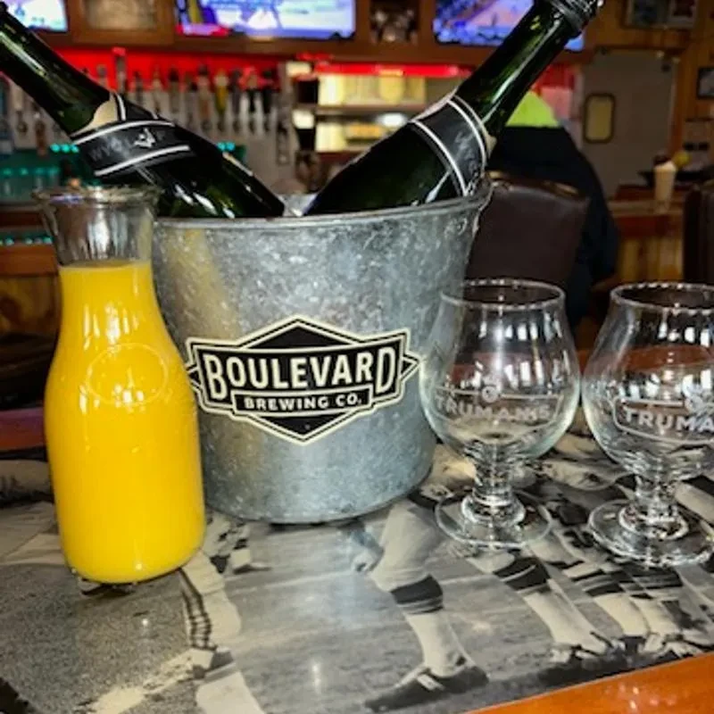 Bar counter with Boulevard Brewing bottles, orange juice, and Truman's glasses.