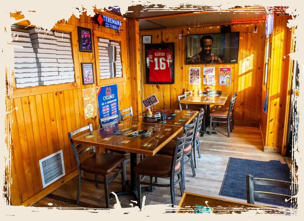Wooden-paneled casual restaurant with dining tables, wall decor, and TV screen.