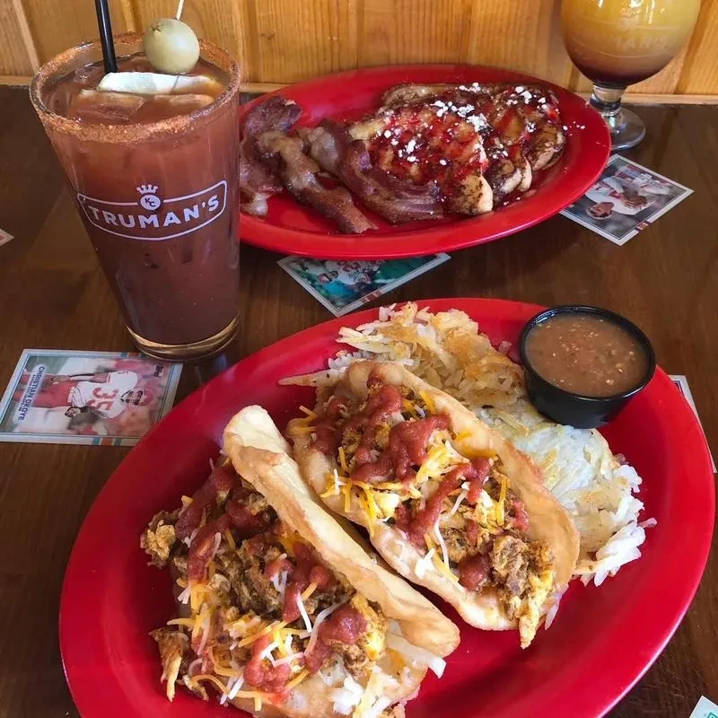 Breakfast tacos, French toast, hash browns, and drinks on a wooden table.
