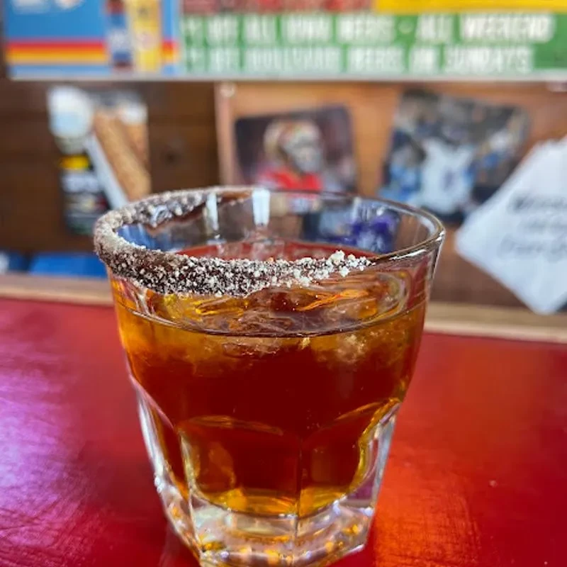 Amber drink in a rocks glass with a sugared rim on a red bar.